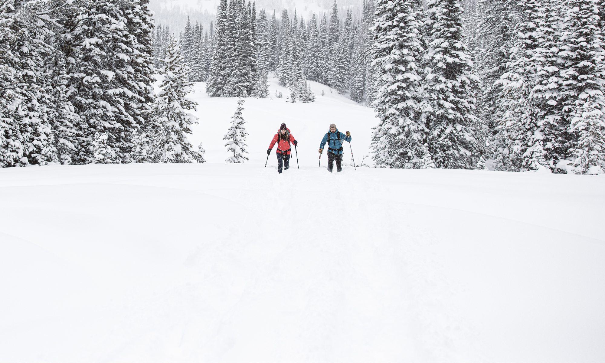 Two people snowshoe in in deep snow wearing Oboz Bridger Insulated hiking boots.