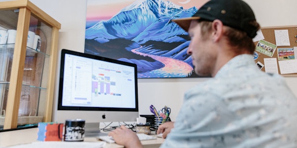 Oboz employee working on a mac computer with cool art in the background