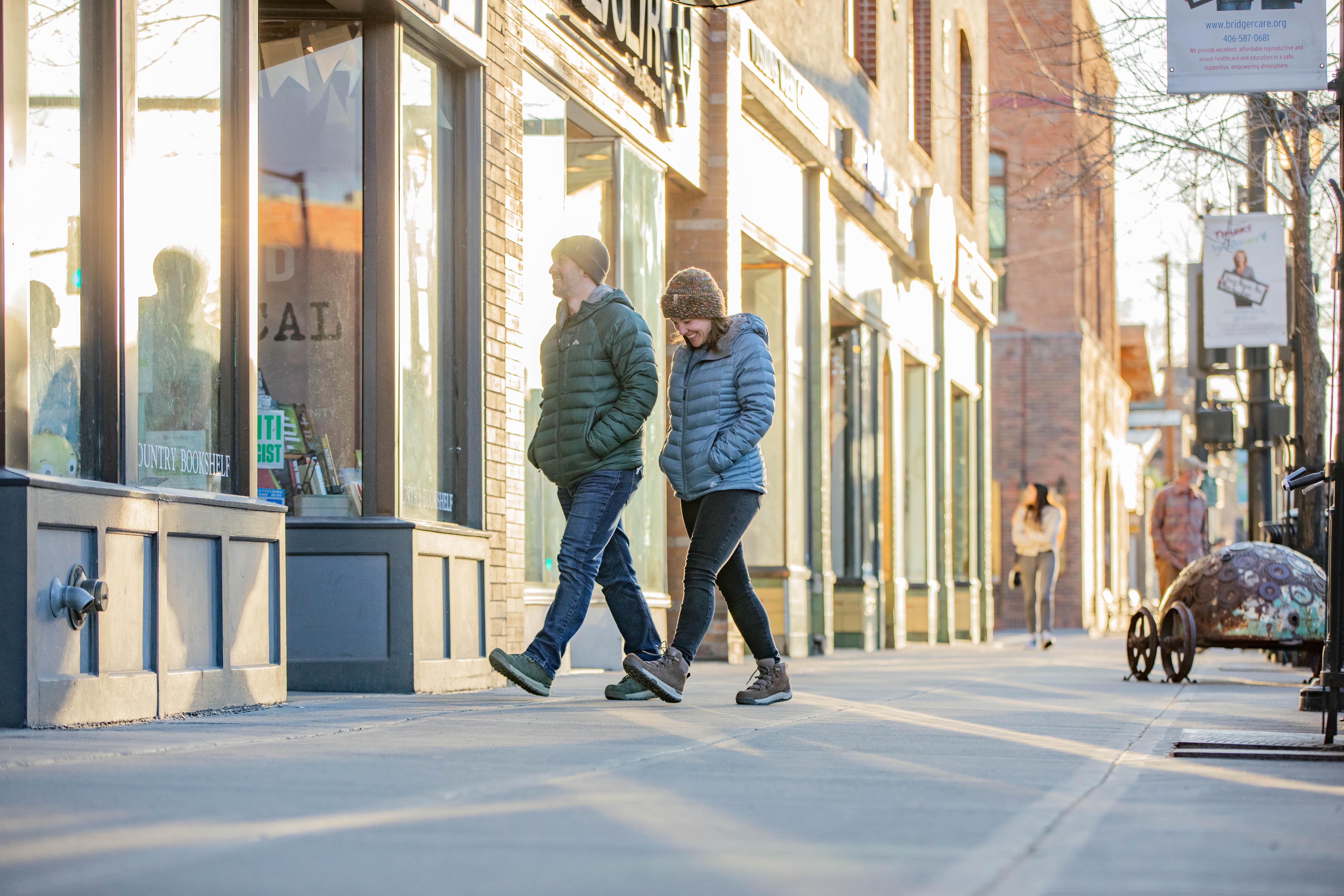A couple strolls through downtown Bozeman while staying warm in puffy jackets and Oboz insulated boots.