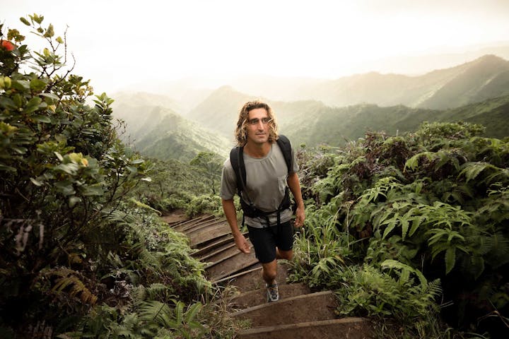 Man hiking up a forest pathway in a lush forest environment while wearing Oboz hiking shoes.