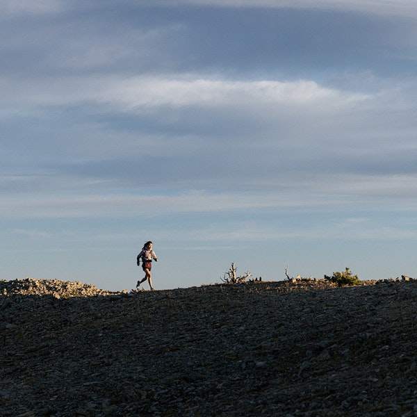 Hiker quickly moving along a ridge in the Bridger mountain range.
