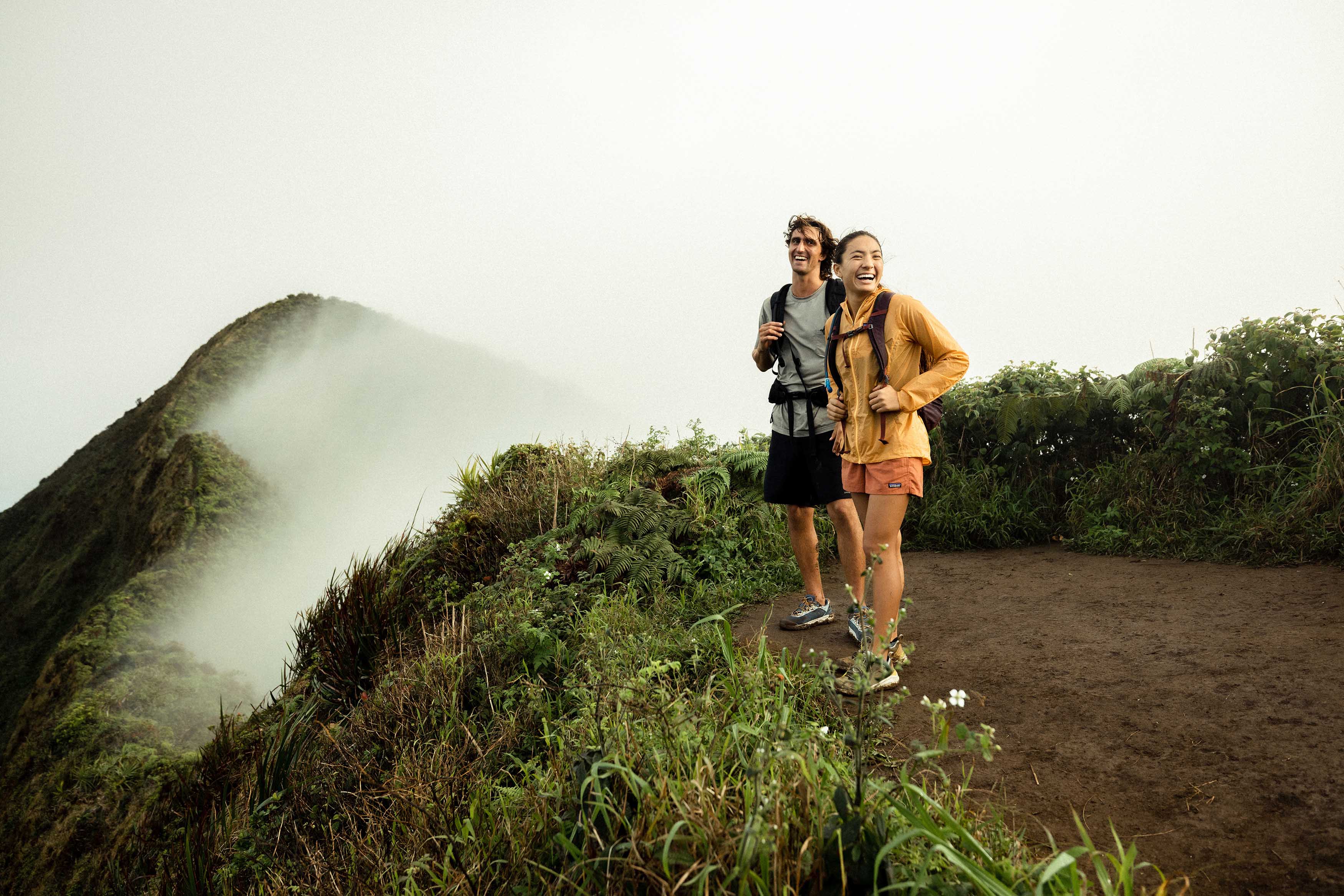 Two hikers at the top of a mountain top in the lush Hawaiian forest. 