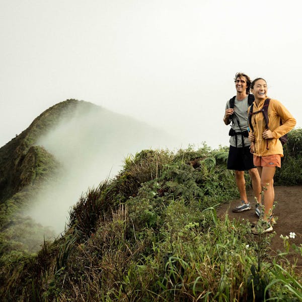 Two hikers in the Oboz Cottonwood Low at the top of a mountain top in the lush Hawaiian forest.