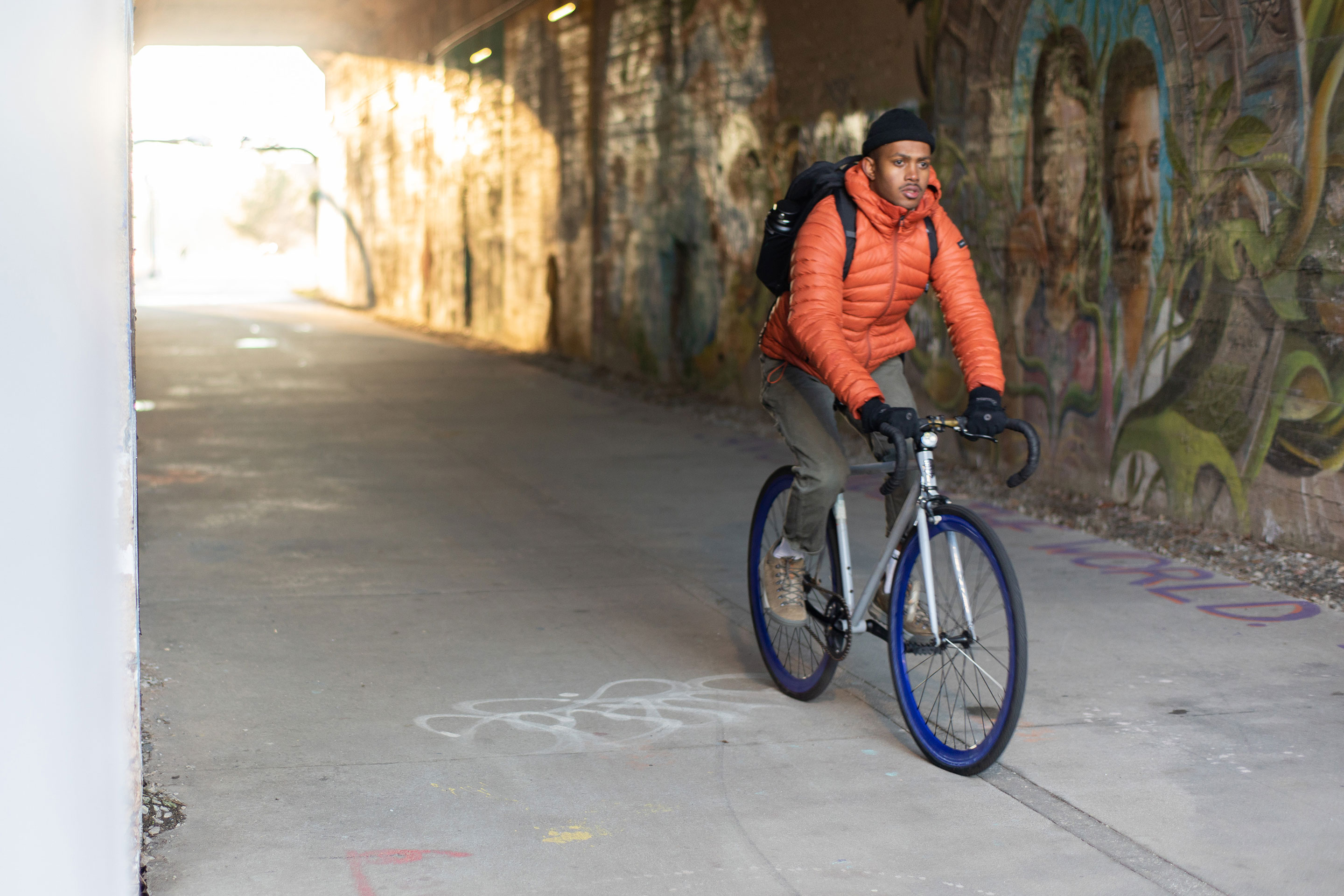 A man rides a bike through a tunnel wearing Oboz Beall casual shoes.