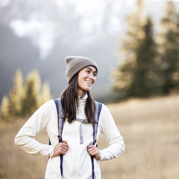 Hiker smiling in a meadow while on a backpacking trip.