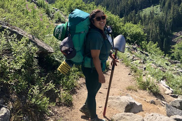 Backpacker carrying a shovel to help work on a trail in the mountains in Oboz Arete hiking boots.