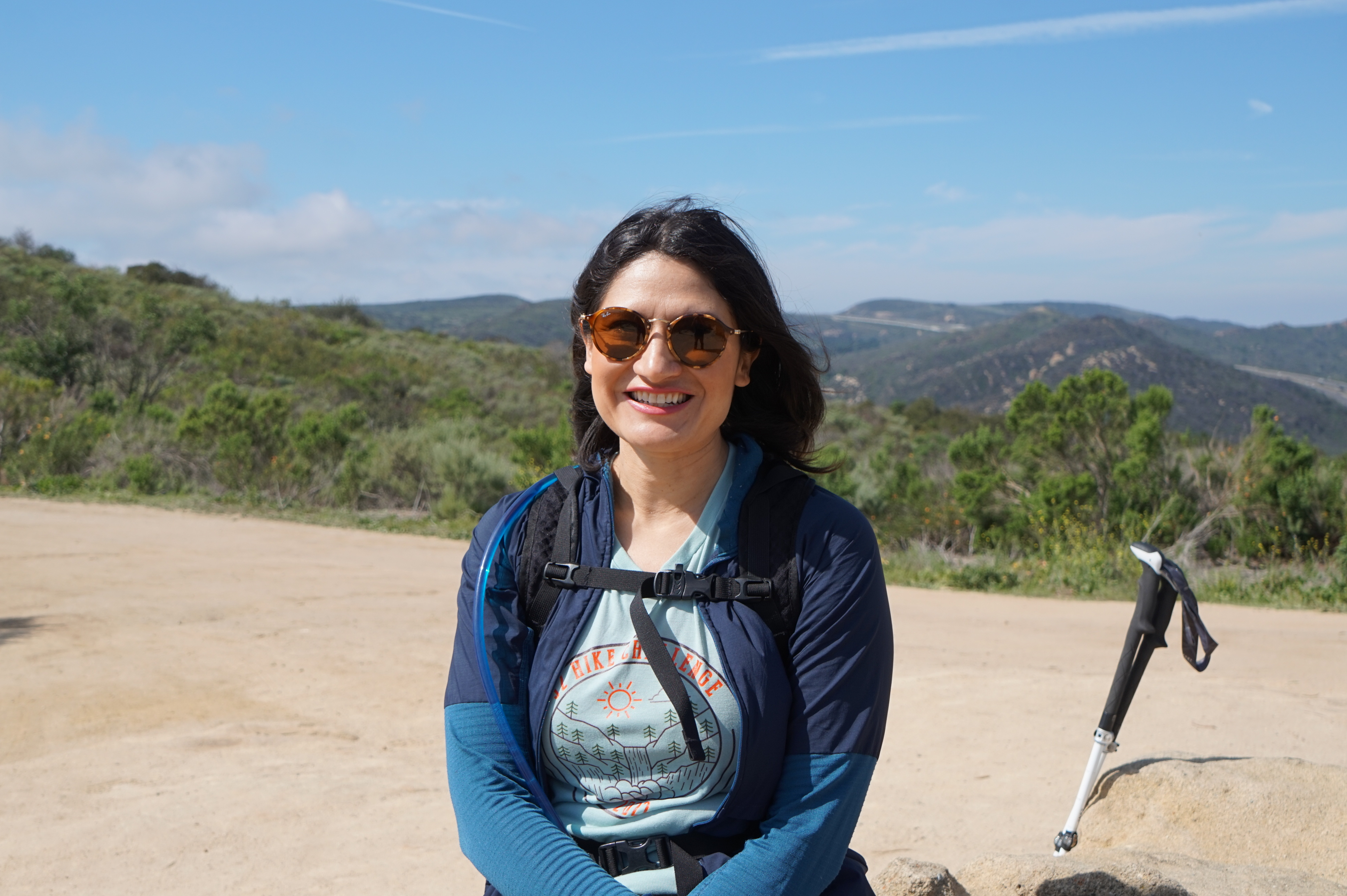 Karla Amador smiling while on a hike in the mountains with some trekking poles.