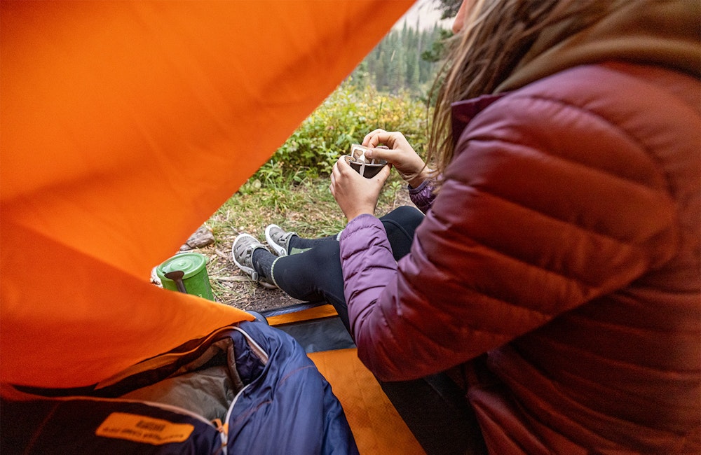 Hiker making coffee at camp while wearing the Oboz Whakata Trail sandal.