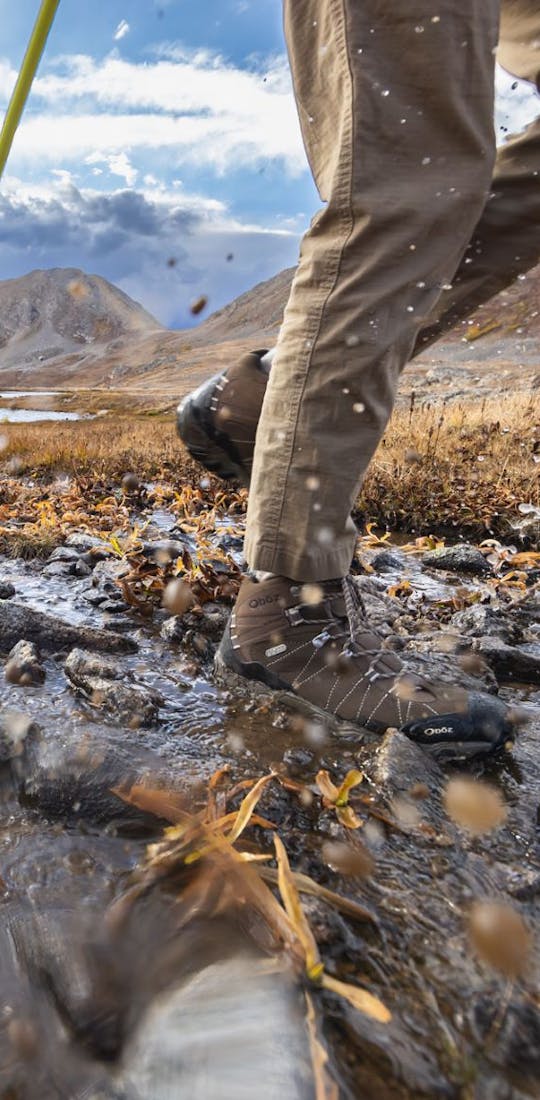 Backpackers crossing a creek on a long trek wearing Oboz Bridger hiking shoes.