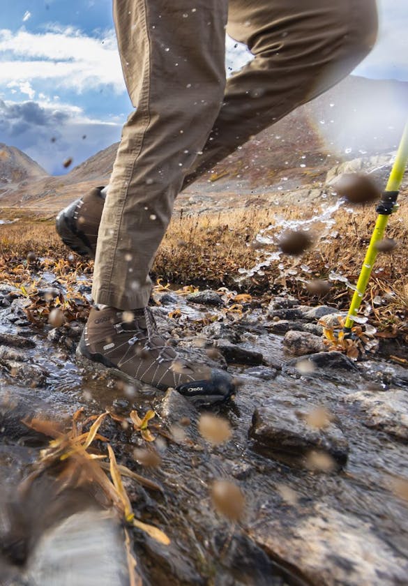 Backpackers crossing a creek on a long trek wearing Oboz Bridger hiking shoes.