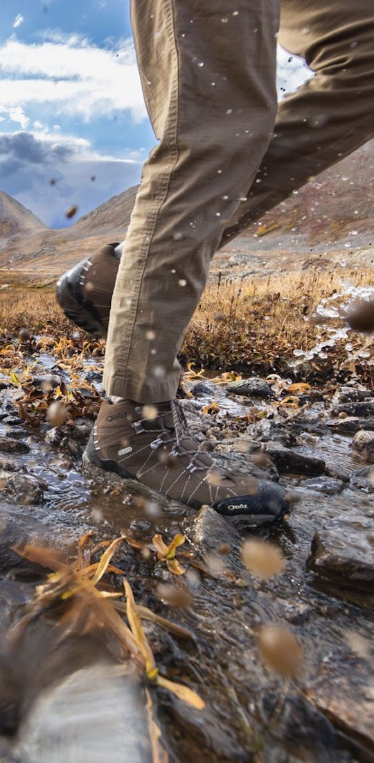 Backpackers crossing a creek on a long trek wearing Oboz Bridger hiking shoes. 