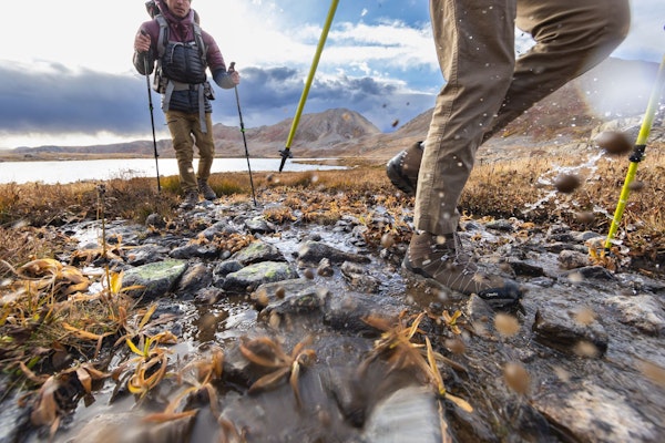 Backpackers crossing a creek on a long trek wearing Oboz Bridger hiking shoes. 