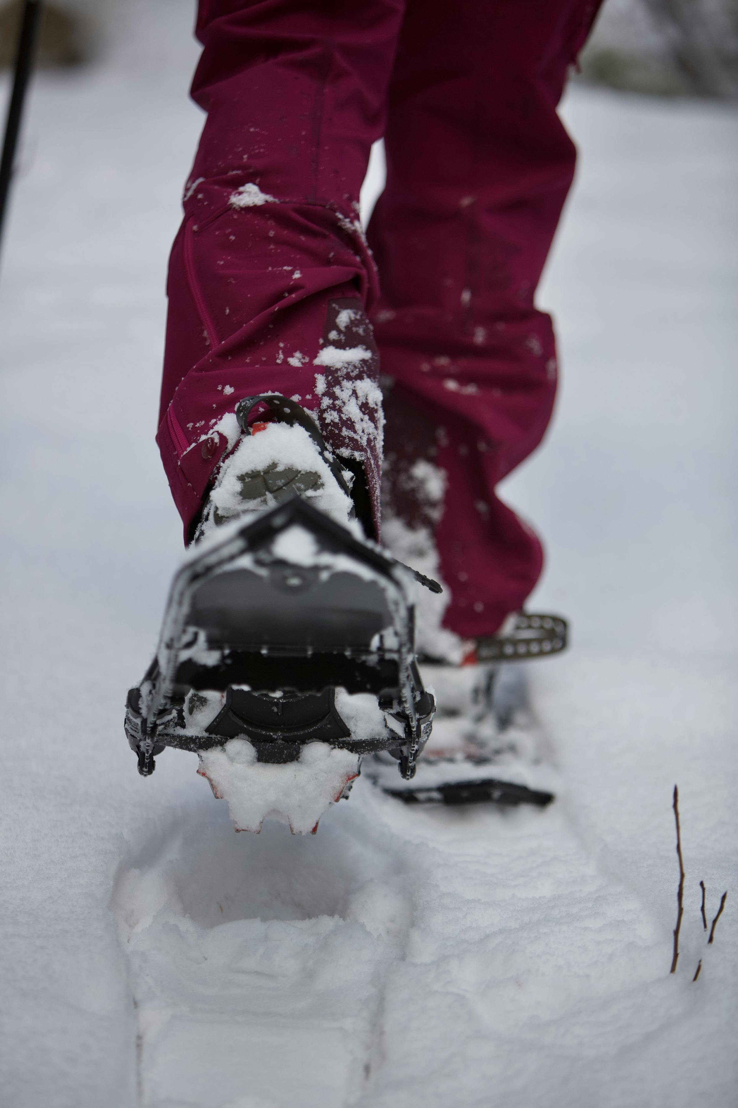 Snowshoer using the proper etiquette on the outside of the trail to avoid walking directly in groomed sections.