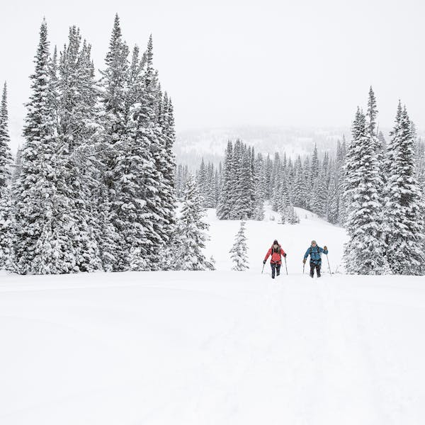 Two people snowshoeing on a snow covered winter trail in Oboz winter boots.