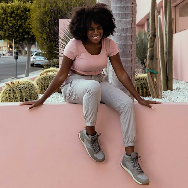 A person relaxing on a ledge wearing Oboz Women's Bozeman Mid casual shoes.