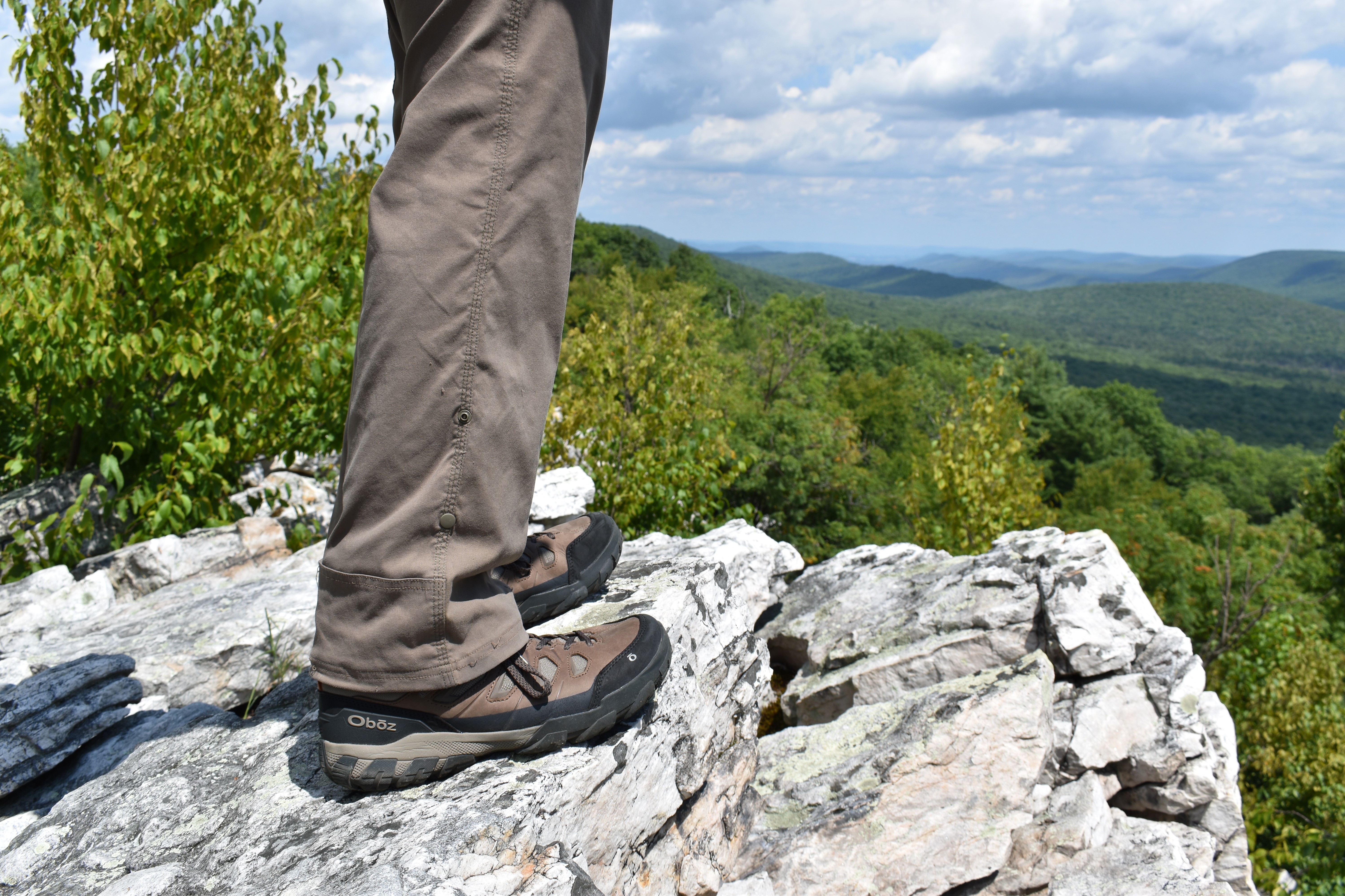 Hiker on rocky overlook wearing Oboz Sawtooth X hiking boots.