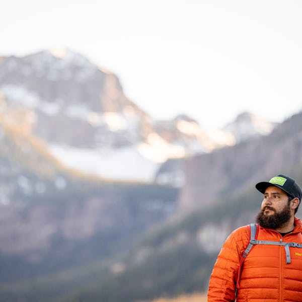 Hiker in Oboz hat takes in mountain view.