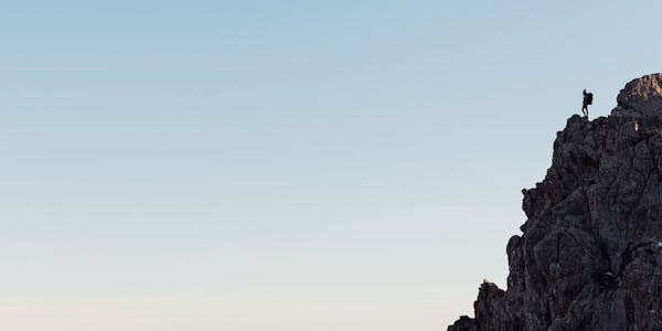 Hiker on top of a mountain peak looking onto the horizon in Oboz hiking boots.
