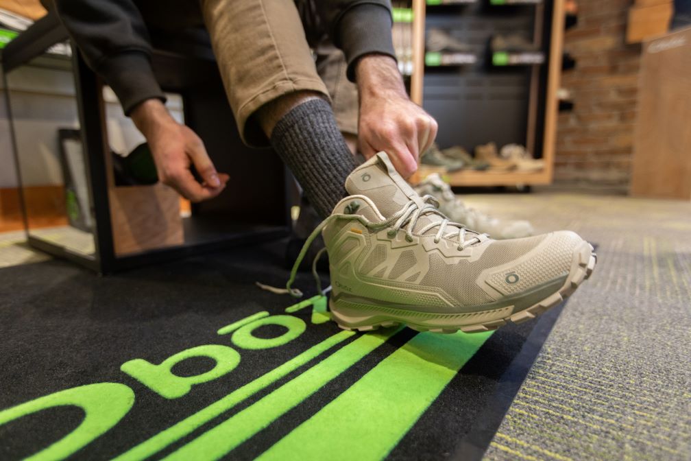 A person puts on an Oboz Katabatic hiking boot at a retail store. 