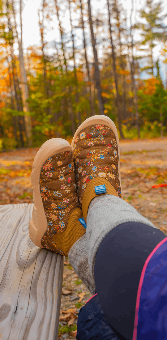 Person lodging their feet up on a campsite table wearing the Skida X Oboz Whakata Puffy during the fall time