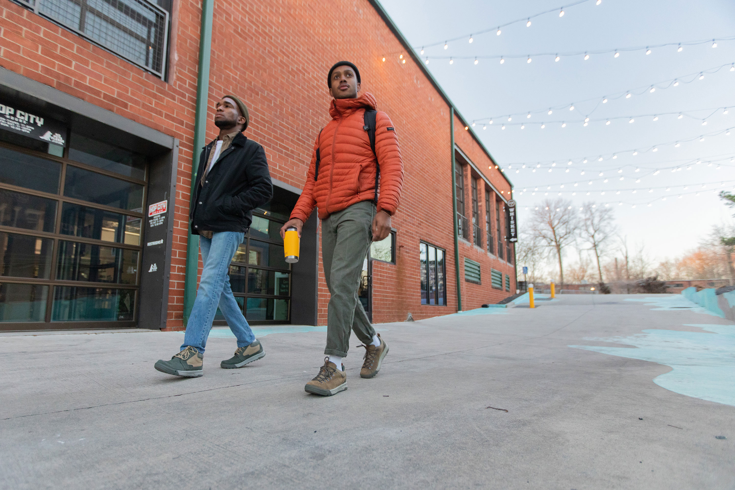 Two men walk in front of a brick building wear the Oboz Burke Chukka and Beall Low casual shoes.