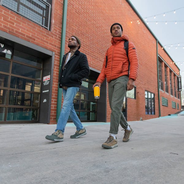 Two men walk in front of a brick building wear the Oboz Burke Chukka and Beall Low casual shoes.
