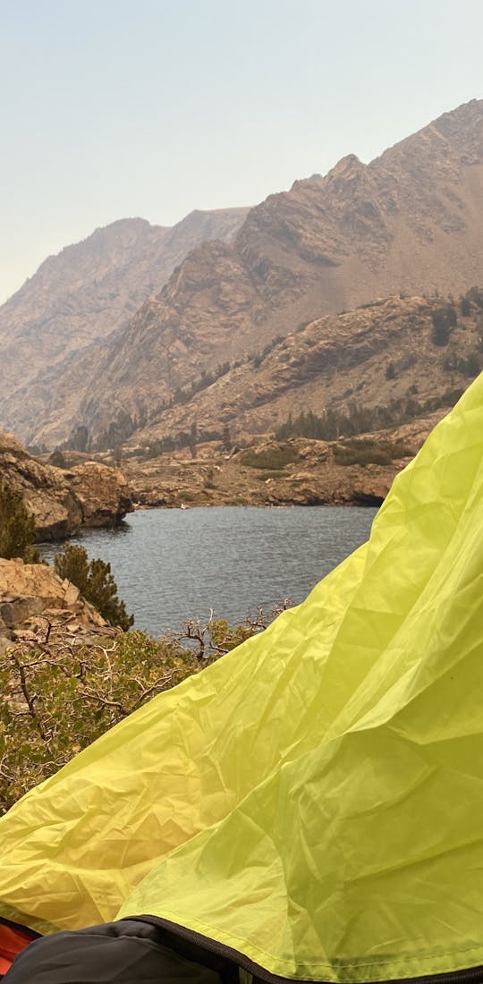 View from inside a tent looking out at a high elevation lake and mountains.