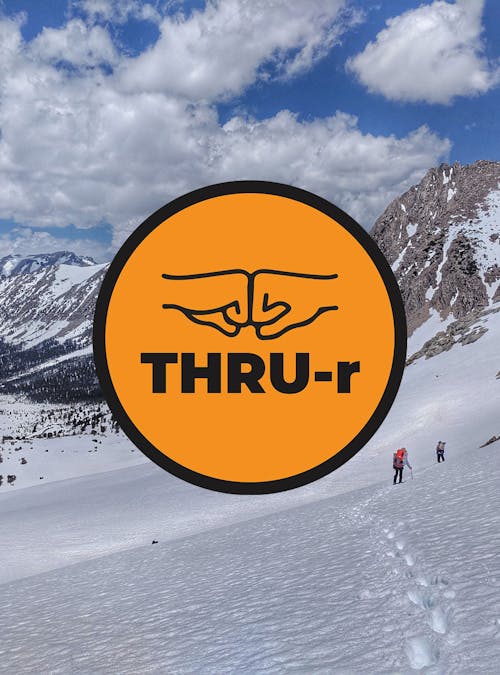 Backpacking on a snow covered trail in winter. THRU-r logo overlayed