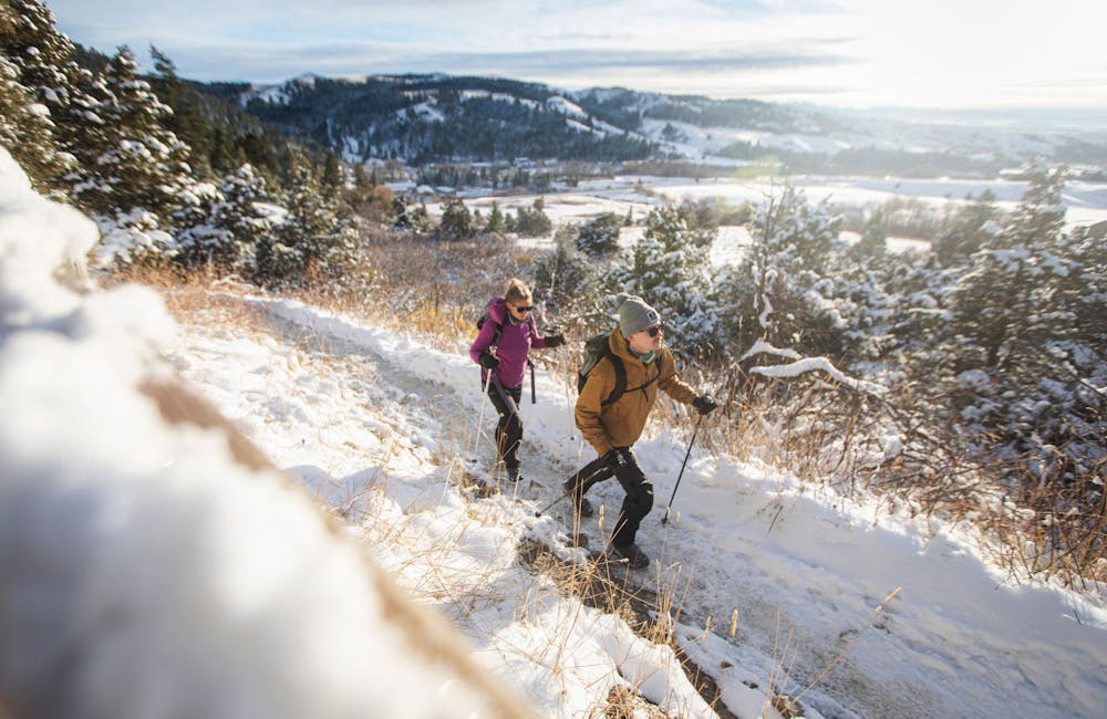 Two hikers on a snowy trail wearing Oboz Footwear Bangtail Insulated Winter Boots.