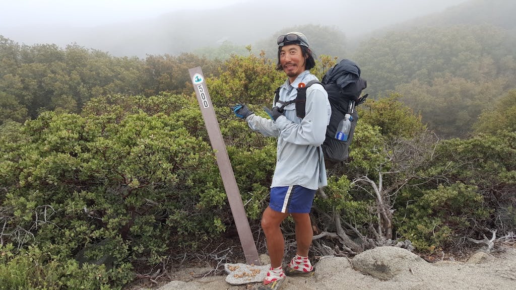 Tyler shows off a mile marker during a hike through wooded terrain. 