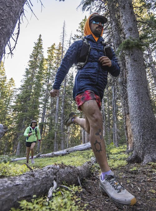 Man fast hiking through a forested trail in Oboz Katabatic hiking shoes.
