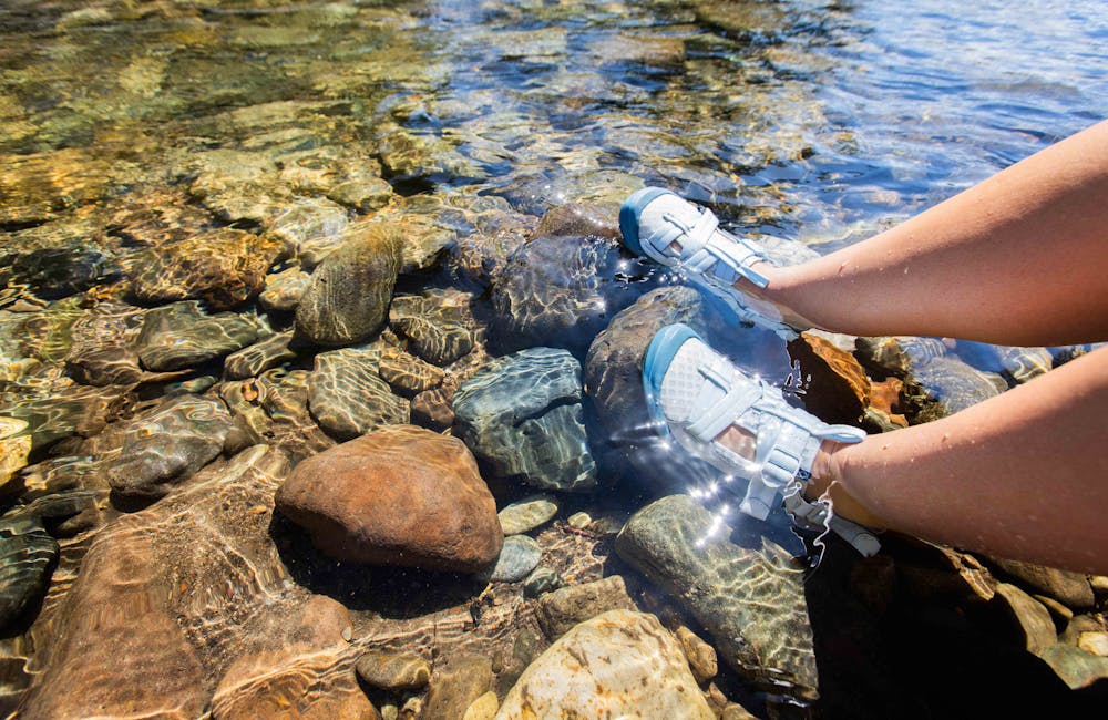 Woman on a river float trip soaking her feet in the water while wearing Oboz Off-Road sandals.
