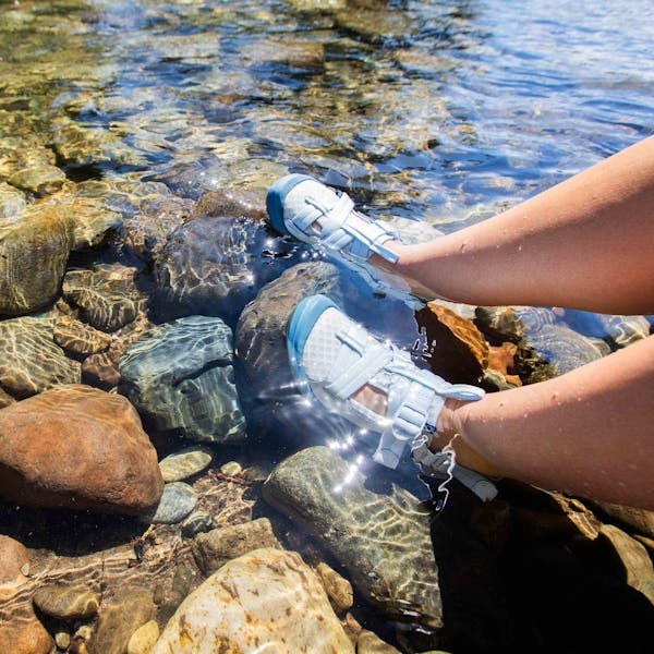 Woman on a river float trip soaking her feet in the water while wearing Oboz sandals.