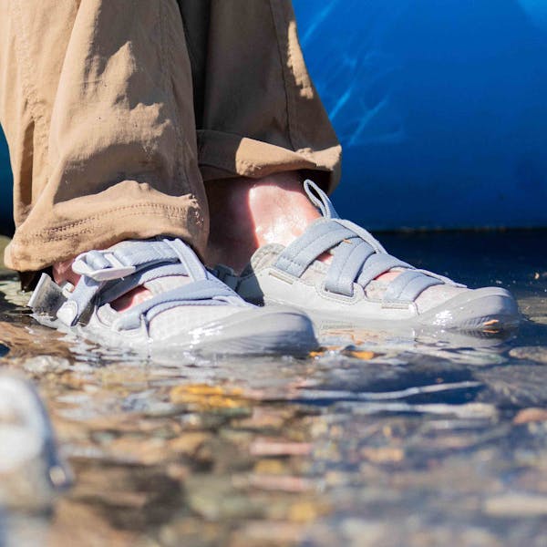 Man wearing Oboz Whakata Off Road sandals in the river next to a raft.