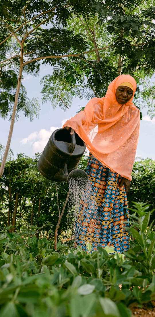 Woman watering plants in a One More Tree farming facility.