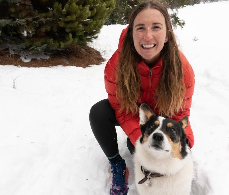Oboz employee smiling with her dog on a winter trail.