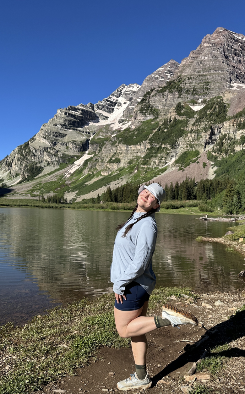 Kylie standing by a mountain lake after a day on the trail. 