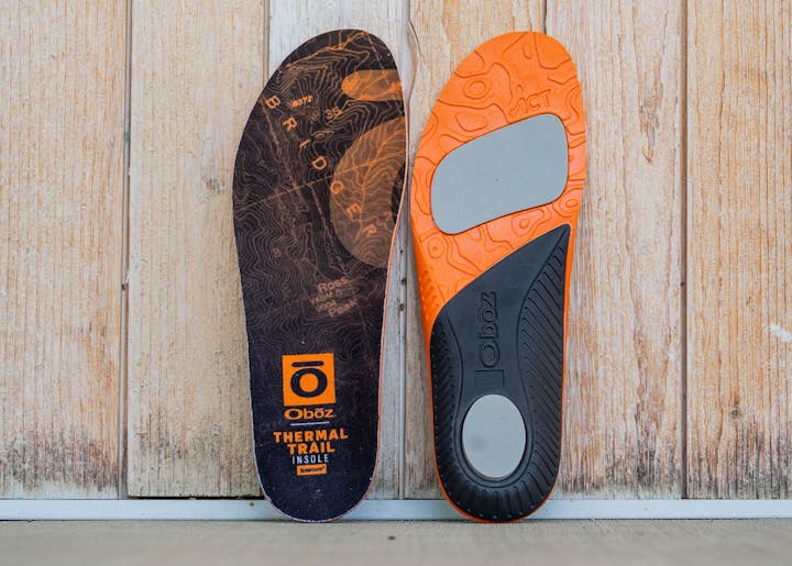 Oboz thermal trail insole up against a wooden wall.
