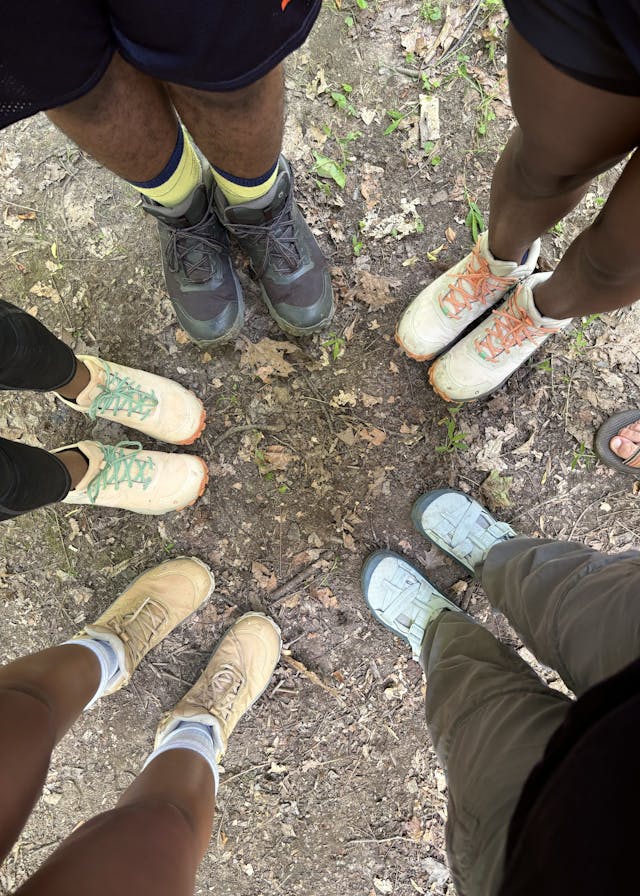 A group of hikers in a circle wearing Oboz hiking shoes