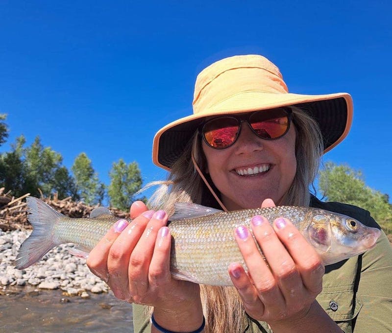 Oboz Footwear employee holding up a trout on a fishing trip.