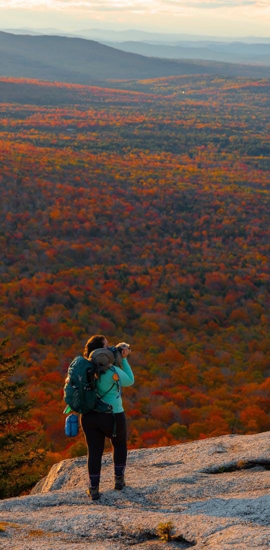 A hiker in Oboz Footwear on a hike through fall foliage.