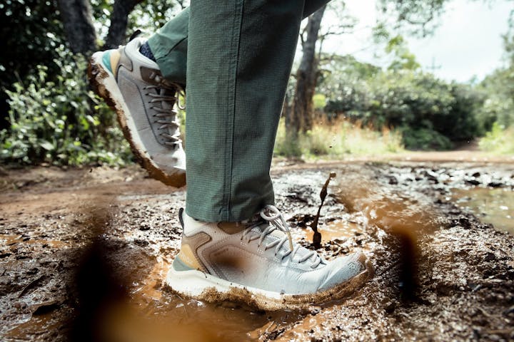 The Oboz Mid Cottonwood hiking boots stepping through a muddy puddle.