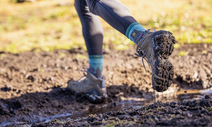 Walking on a muddy hiking trail in the Oboz Sawtooth II Mid backpacking boots.