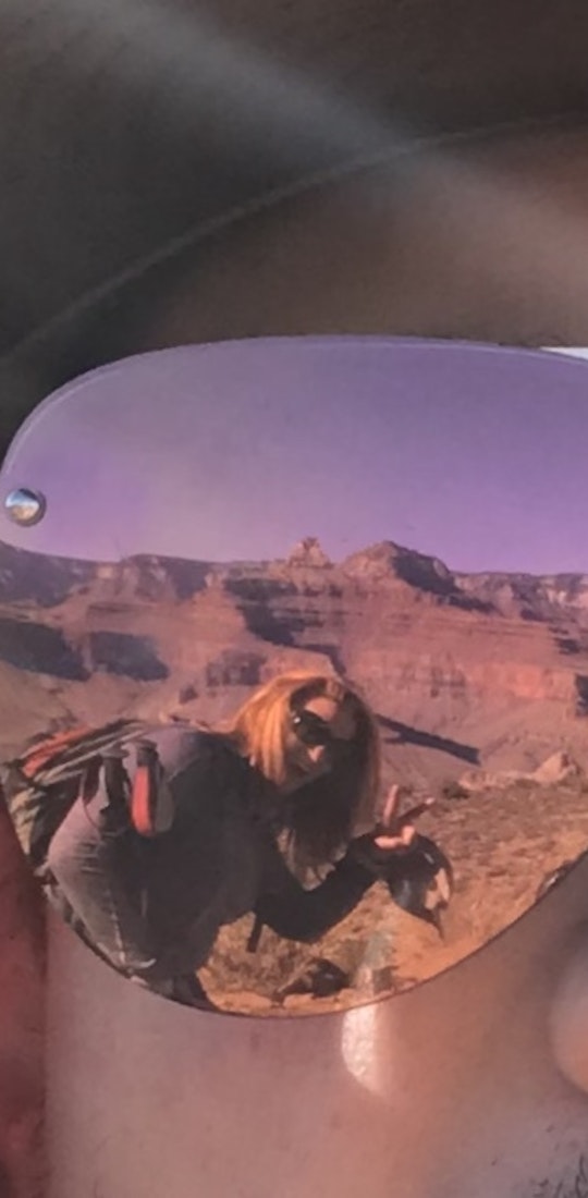 The reflection of glasses showing a hiker and layers of a canyon