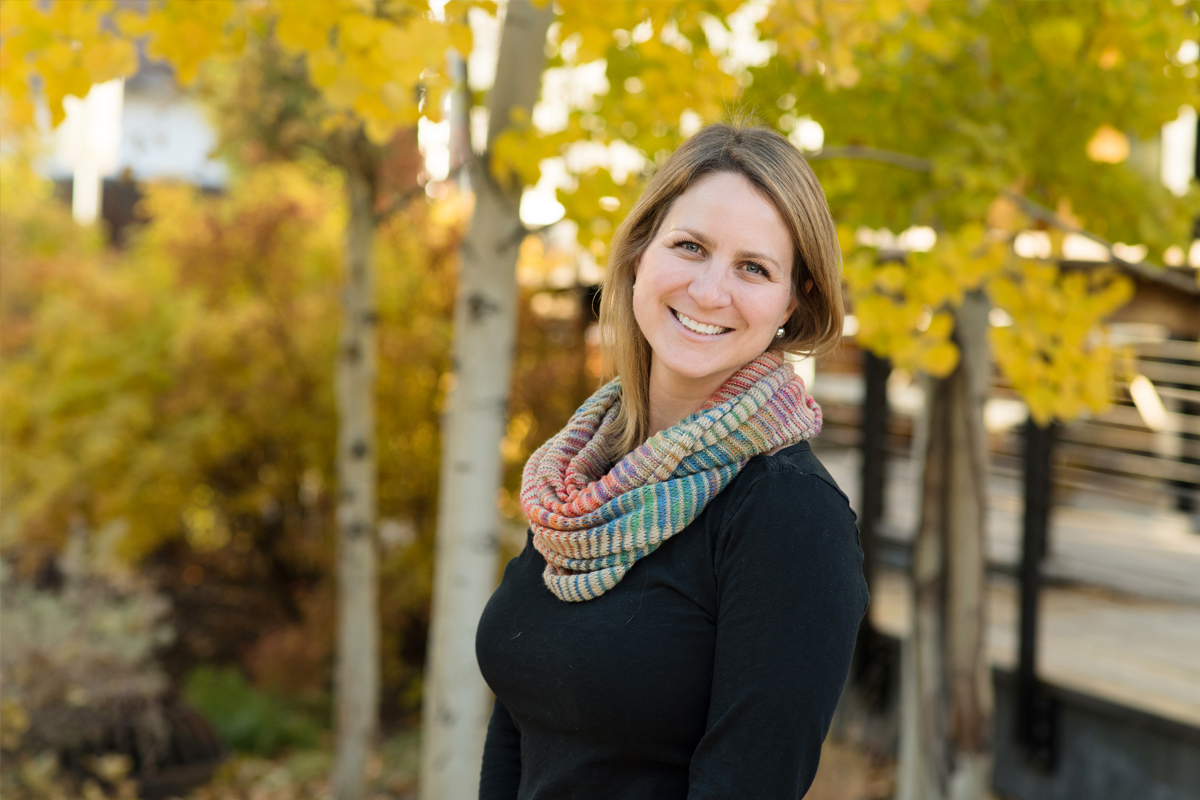 Woman smiling in front of a colorful Aspen Grove