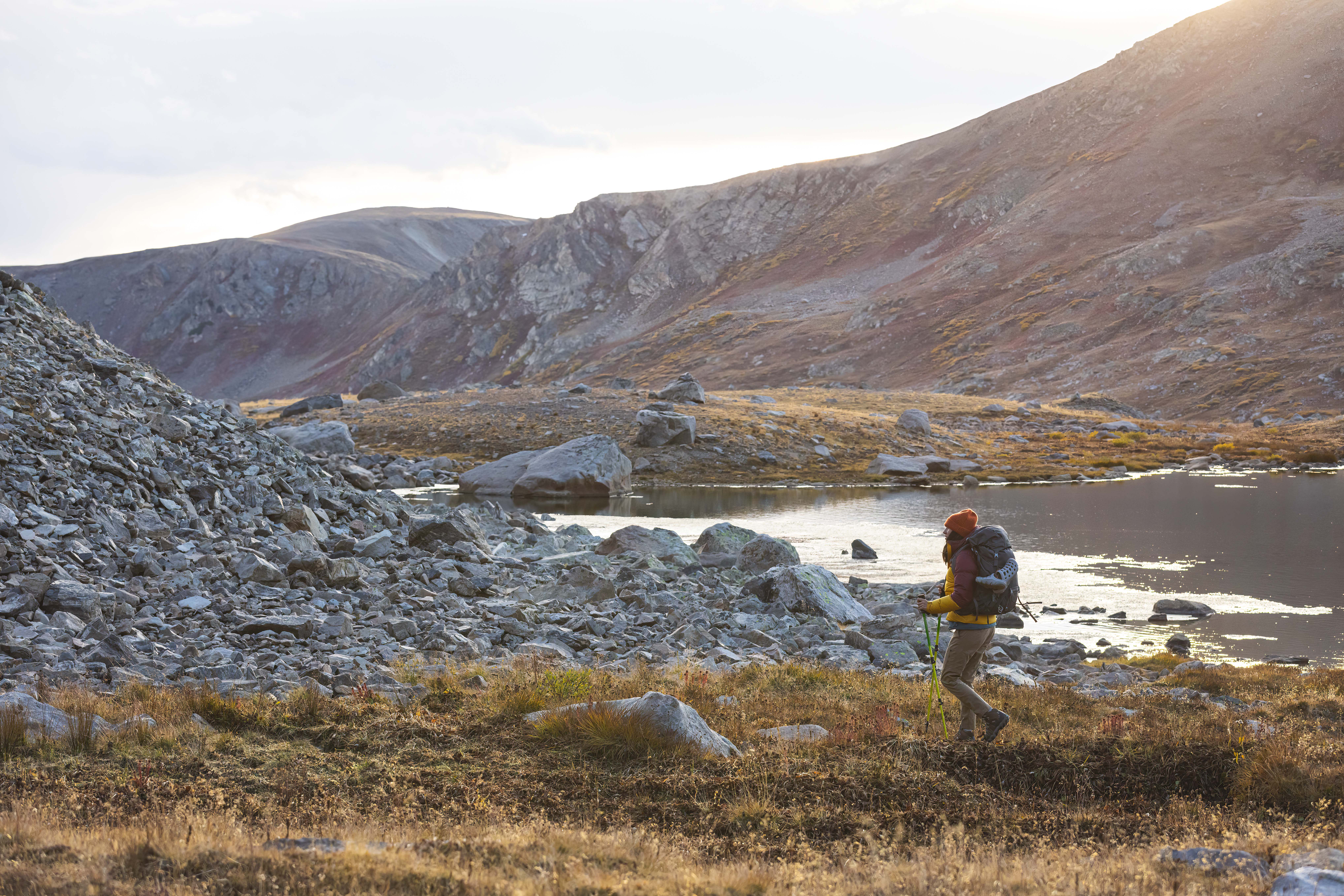 Woman hiking in Oboz hiking boots past an alpine lake in the fall.