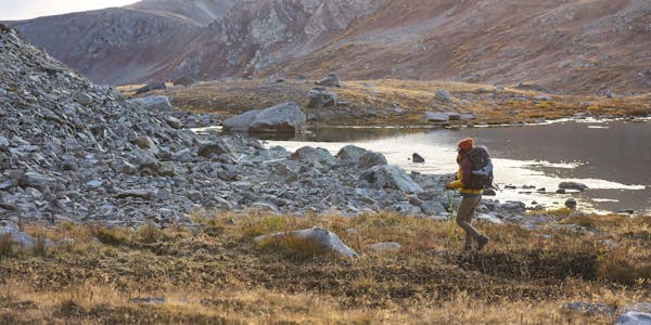 Woman hiking in Oboz hiking boots past an alpine lake in the fall.