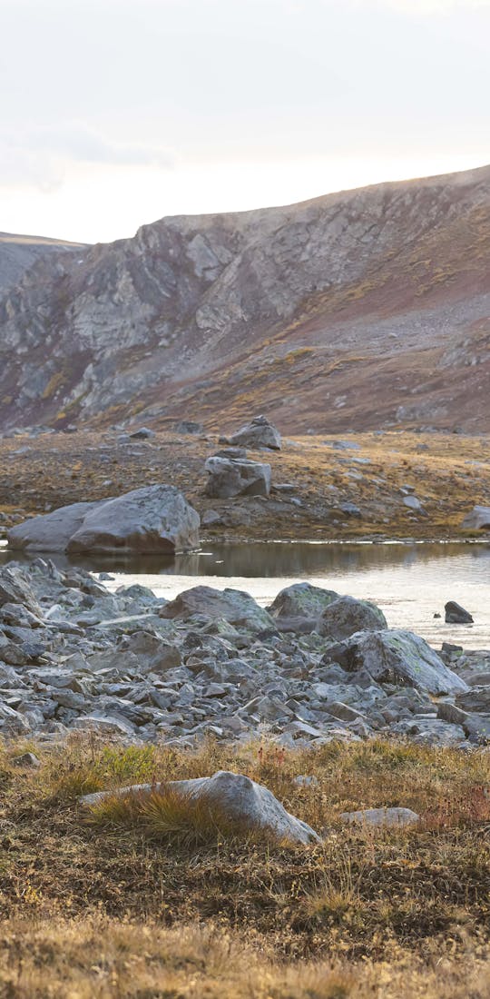 Woman hiking in Oboz hiking boots past an alpine lake in the fall.