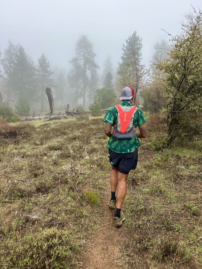 A long-distance hiker moves along a misty trail in Oboz fast trail shoes