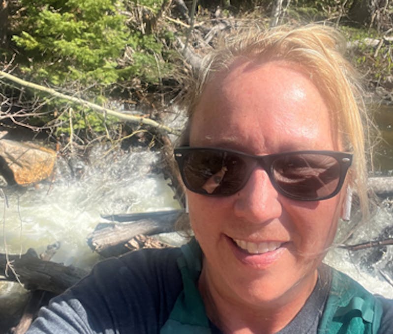Oboz Footwear employee hiking by a rushing creek.